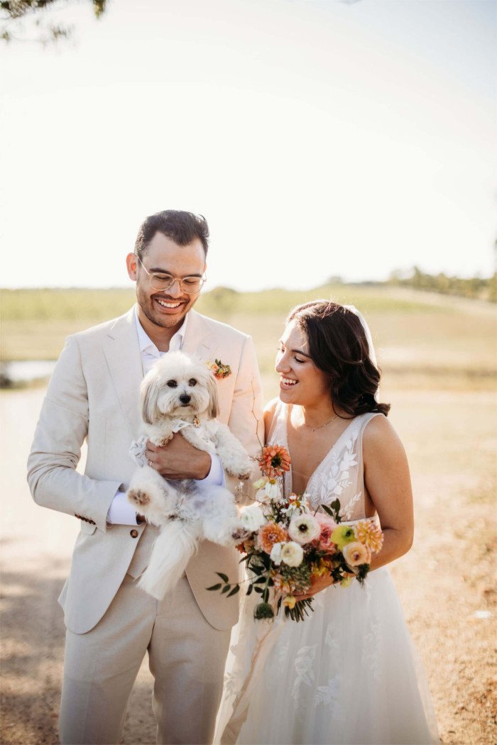 A couple with their small white dog on the lawn