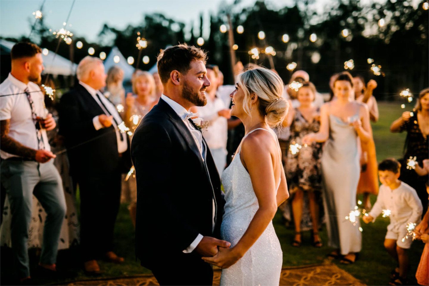 A first dance under festoon lights, guests holding sparklers