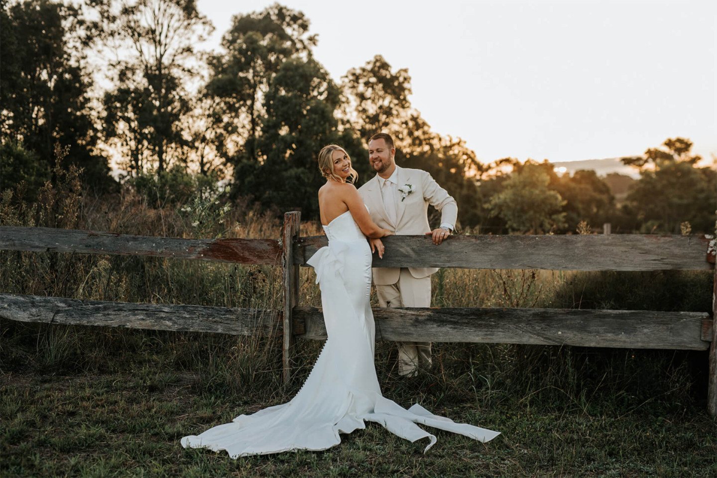 A couple at the paddock fence at sunset